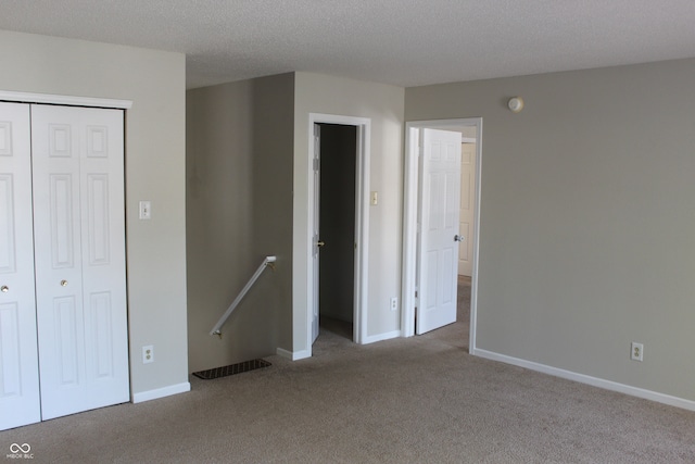 unfurnished bedroom with a textured ceiling, carpet flooring, and a closet