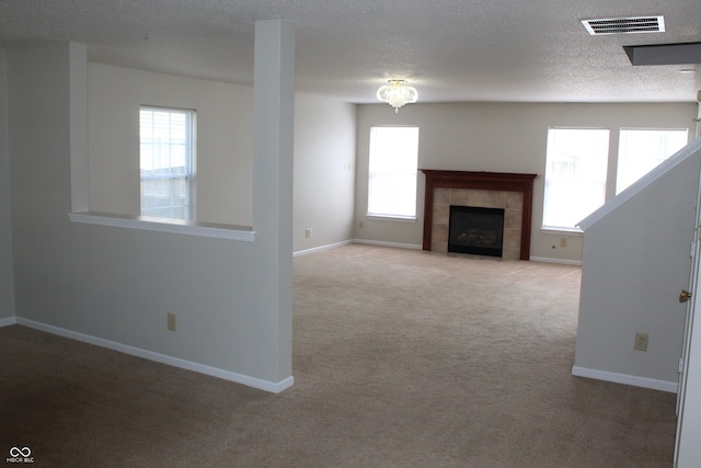 unfurnished living room with a textured ceiling, light colored carpet, and a fireplace