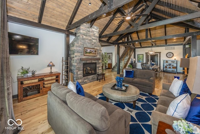 living room featuring beam ceiling, a fireplace, light wood-type flooring, and wood ceiling