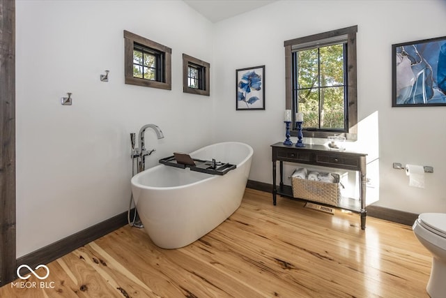 bathroom featuring hardwood / wood-style floors, a washtub, and toilet