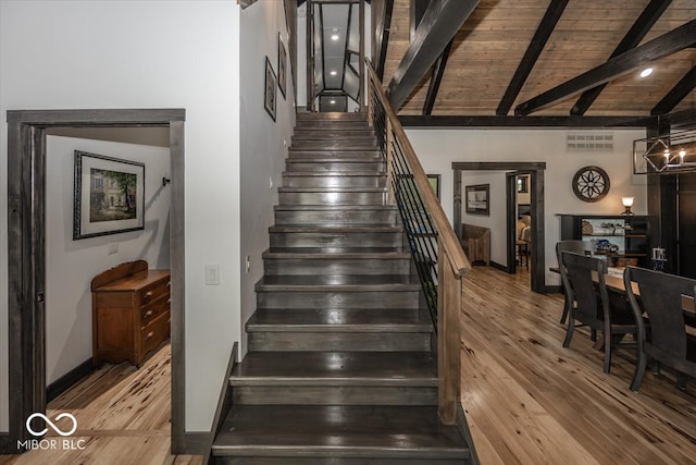 stairs with vaulted ceiling with beams, a notable chandelier, hardwood / wood-style floors, and wooden ceiling