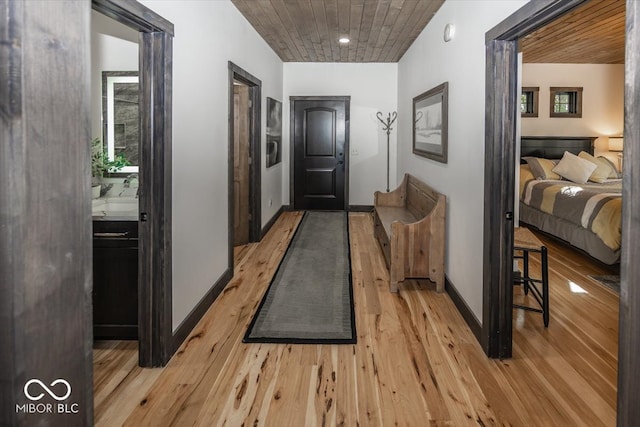 corridor featuring light wood-type flooring and wood ceiling