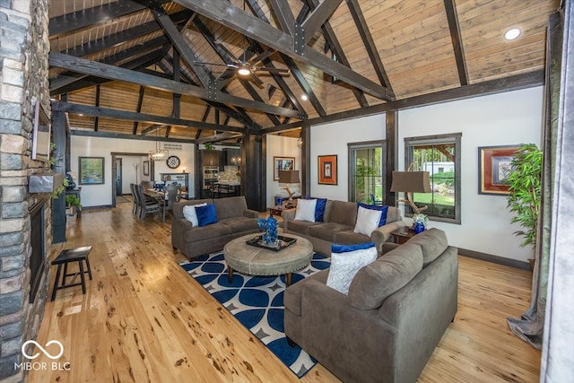 living room with beam ceiling, light hardwood / wood-style floors, ceiling fan, and a fireplace