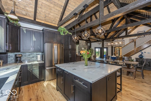 kitchen featuring a breakfast bar, pendant lighting, a center island, light hardwood / wood-style flooring, and stainless steel fridge