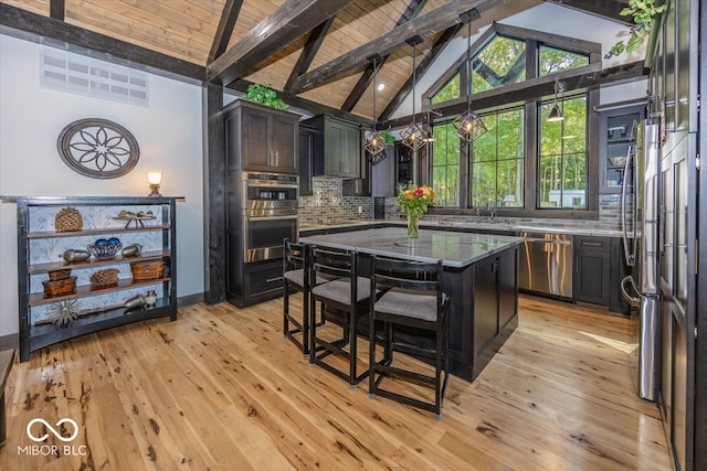 kitchen with beamed ceiling, stainless steel appliances, light hardwood / wood-style floors, and a center island