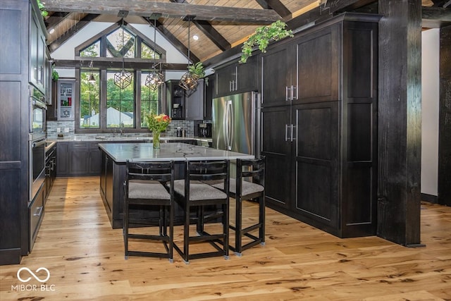 kitchen featuring a breakfast bar, lofted ceiling with beams, light hardwood / wood-style floors, and a center island