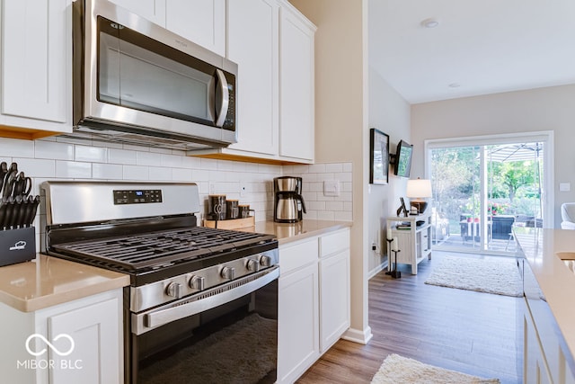 kitchen featuring stainless steel appliances, light hardwood / wood-style floors, tasteful backsplash, and white cabinetry