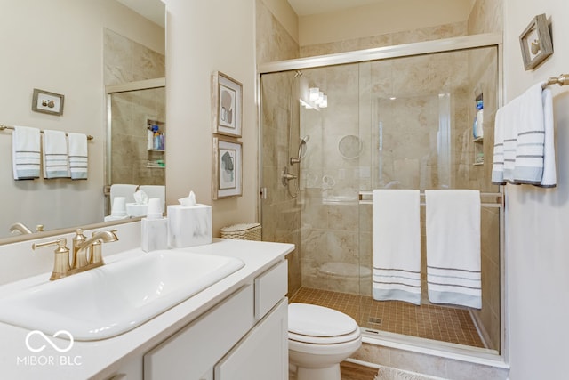 bathroom featuring a shower with door, vanity, and toilet