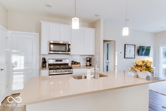 kitchen featuring hanging light fixtures, a center island with sink, sink, and stainless steel appliances