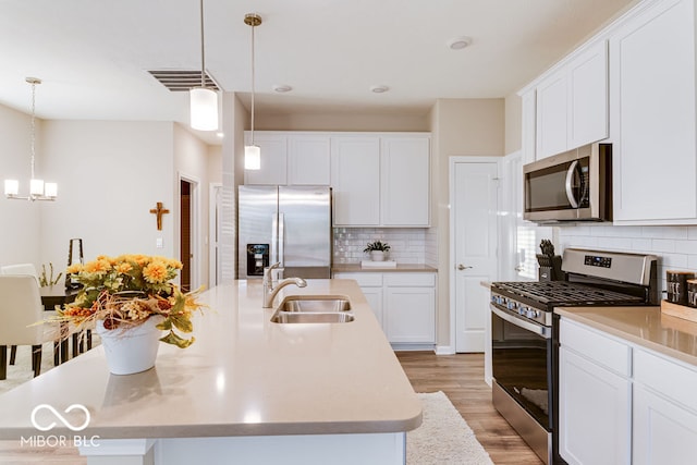 kitchen featuring a center island with sink, light hardwood / wood-style floors, stainless steel appliances, and decorative light fixtures