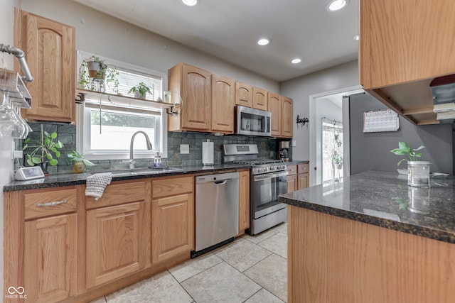 kitchen with dark stone countertops, appliances with stainless steel finishes, backsplash, and sink