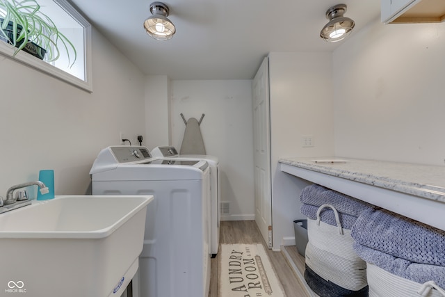 washroom featuring separate washer and dryer, light hardwood / wood-style floors, and sink