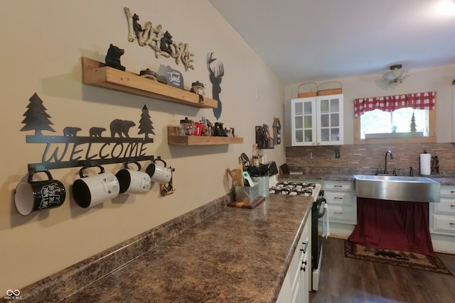 kitchen with stainless steel gas range oven, backsplash, sink, and white cabinetry