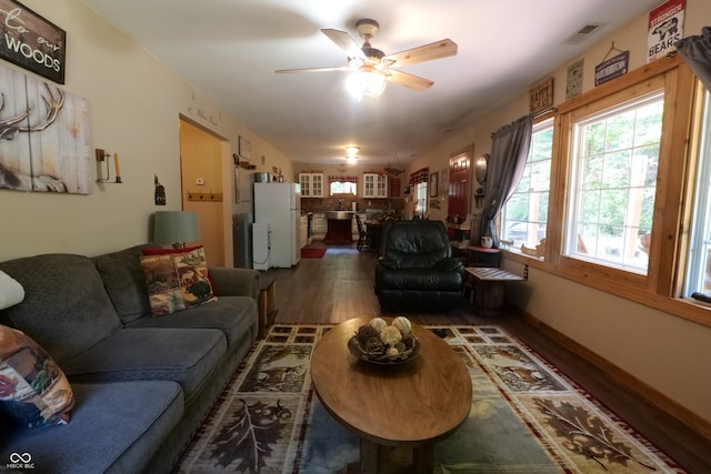 living room featuring dark wood-type flooring and ceiling fan