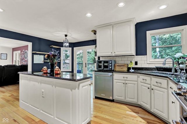 kitchen featuring light hardwood / wood-style flooring, white cabinets, appliances with stainless steel finishes, and decorative light fixtures