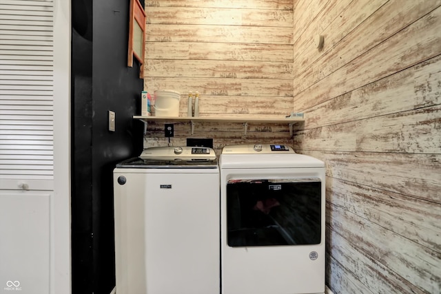 laundry room featuring wooden walls and washer and dryer