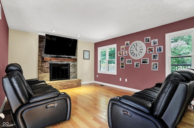 living room with a brick fireplace and light hardwood / wood-style floors