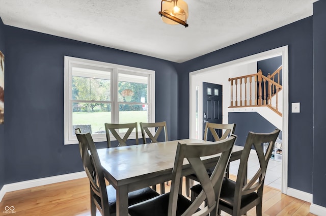 dining space with light wood-type flooring and a textured ceiling