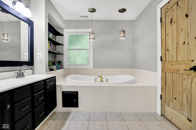 bathroom with tile patterned flooring, tiled bath, and vanity