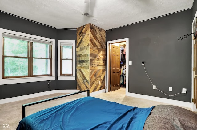 bedroom featuring a closet, a textured ceiling, a walk in closet, and carpet floors