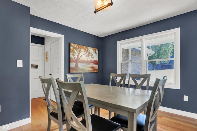 dining space featuring light wood-type flooring and a textured ceiling