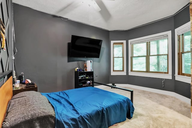 carpeted bedroom featuring ceiling fan and a textured ceiling