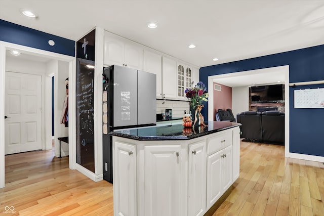 kitchen featuring backsplash, white cabinetry, refrigerator, dark stone counters, and light hardwood / wood-style floors