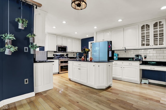 kitchen featuring light wood-type flooring, a center island, white cabinets, decorative backsplash, and stainless steel appliances