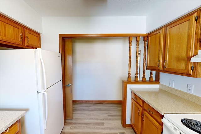 kitchen with light hardwood / wood-style floors, white fridge, extractor fan, and light stone counters