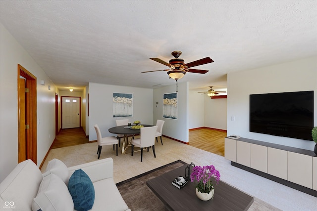 living room featuring ceiling fan, a textured ceiling, and light hardwood / wood-style flooring