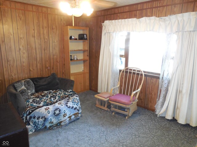 bedroom featuring carpet flooring, wooden walls, and ceiling fan