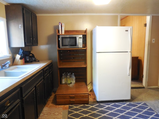 kitchen featuring ornamental molding, white refrigerator, and sink