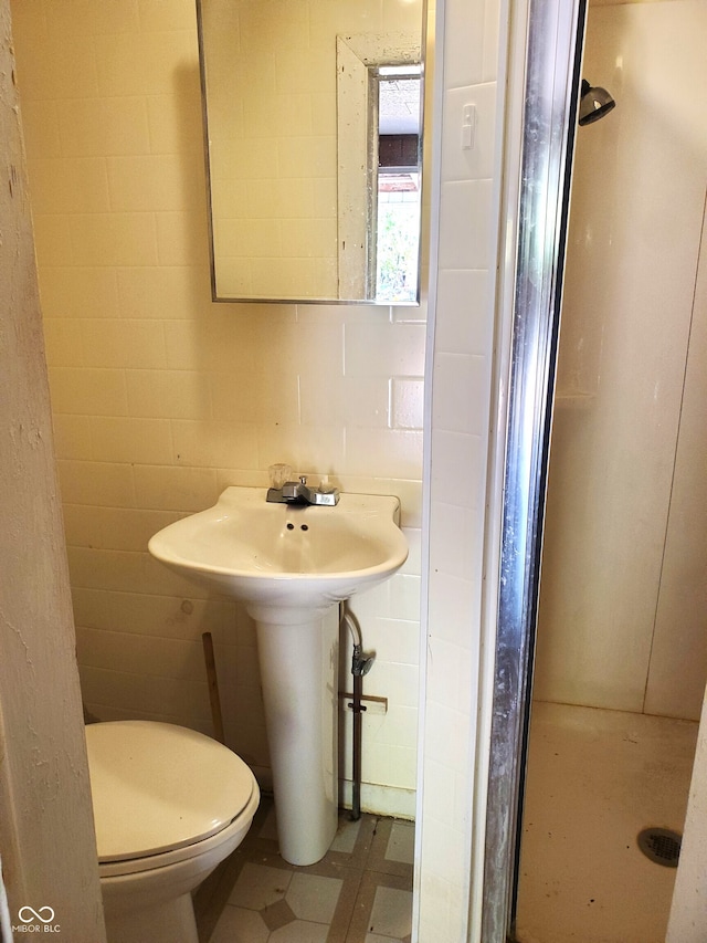 bathroom with a shower, tile walls, and toilet