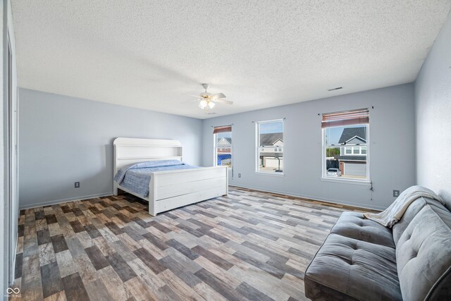 bedroom with hardwood / wood-style flooring, ceiling fan, and a textured ceiling