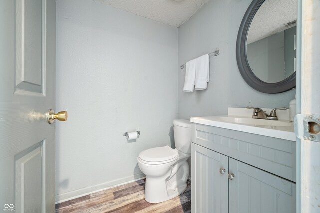 bathroom with vanity, toilet, wood-type flooring, and a textured ceiling