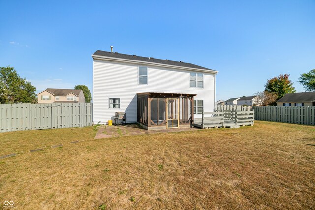 rear view of house featuring a deck and a lawn