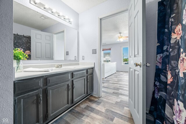 bathroom featuring ceiling fan, vanity, wood-type flooring, and a textured ceiling