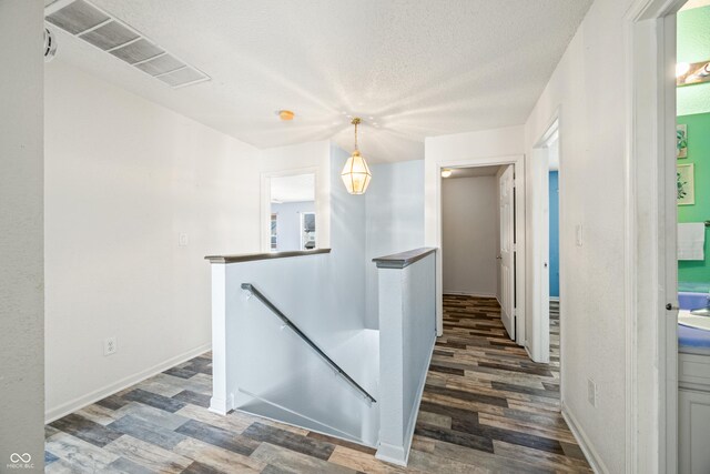 corridor featuring a textured ceiling and dark hardwood / wood-style floors