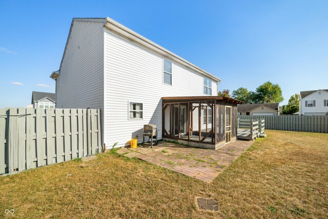 back of property featuring a yard, a sunroom, and a patio