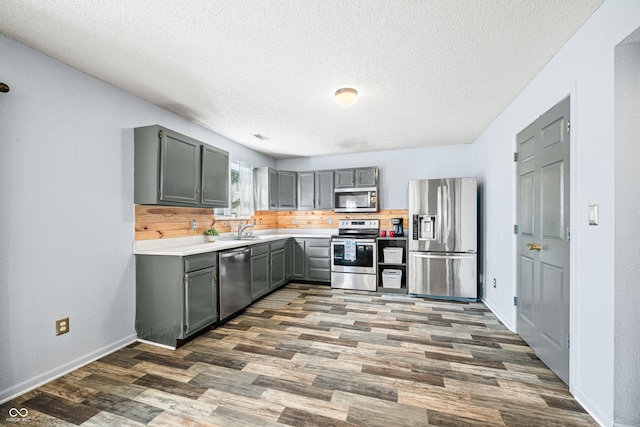 kitchen featuring tasteful backsplash, sink, stainless steel appliances, dark hardwood / wood-style floors, and a textured ceiling