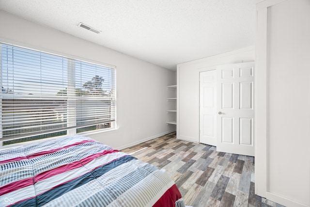 unfurnished bedroom featuring light wood-type flooring, a closet, and a textured ceiling