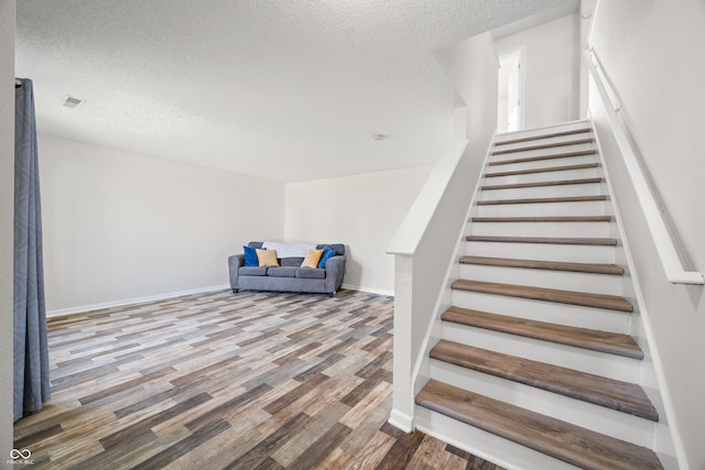 stairway with hardwood / wood-style flooring and a textured ceiling