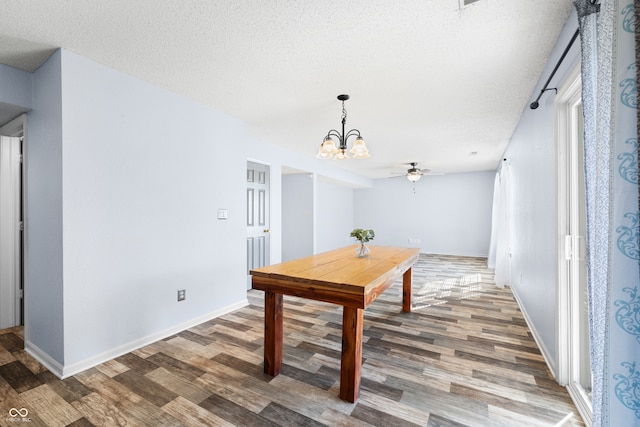 dining space with ceiling fan with notable chandelier, dark hardwood / wood-style flooring, and a textured ceiling