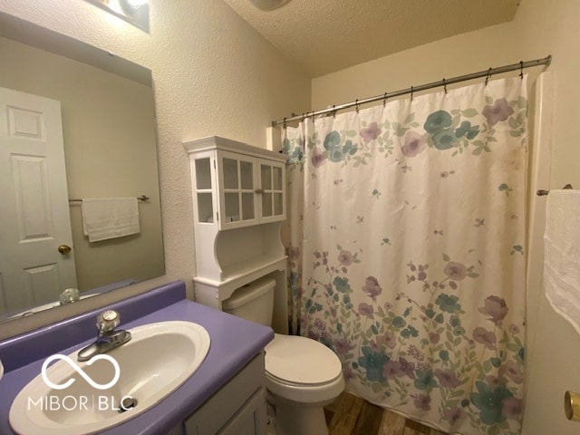 bathroom featuring hardwood / wood-style floors, vanity, walk in shower, toilet, and a textured ceiling