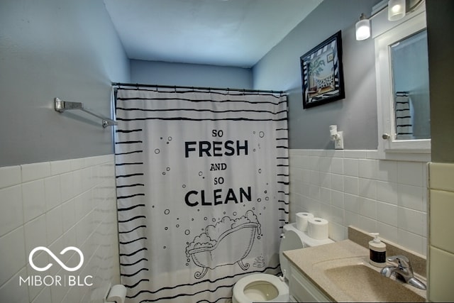 bathroom with vanity, tile walls, toilet, and curtained shower