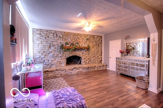 living room featuring a textured ceiling, a fireplace, hardwood / wood-style floors, and ceiling fan