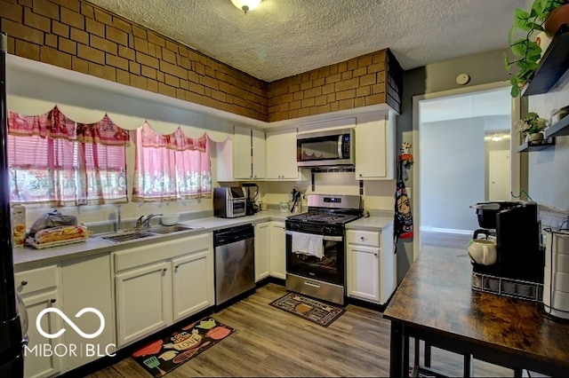 kitchen with white cabinets, hardwood / wood-style flooring, appliances with stainless steel finishes, and sink