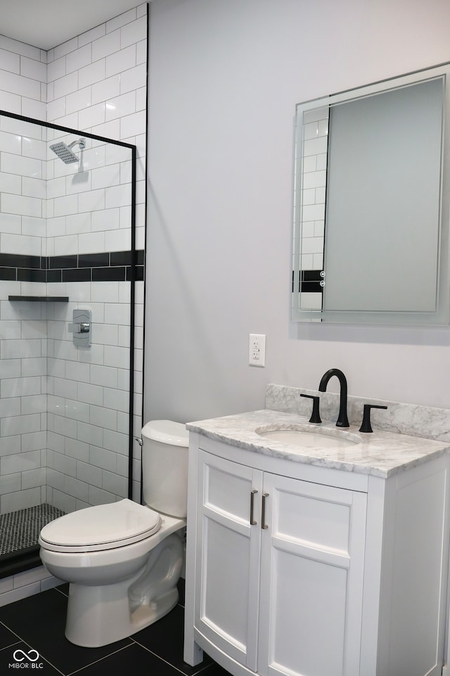 bathroom with tiled shower, vanity, toilet, and tile patterned flooring