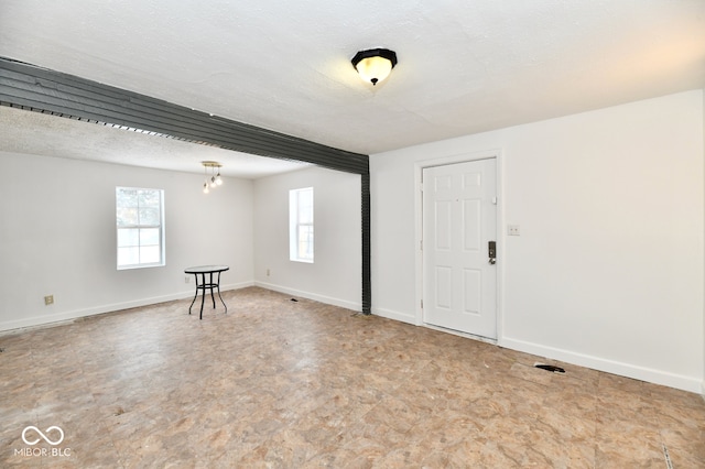 spare room featuring a textured ceiling and an inviting chandelier