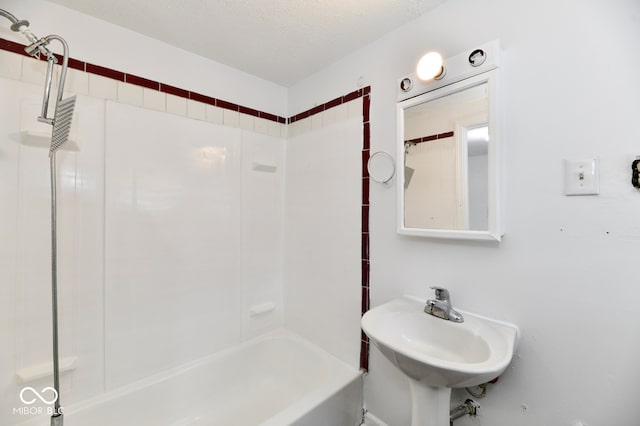 bathroom with sink, a textured ceiling, and tiled shower / bath